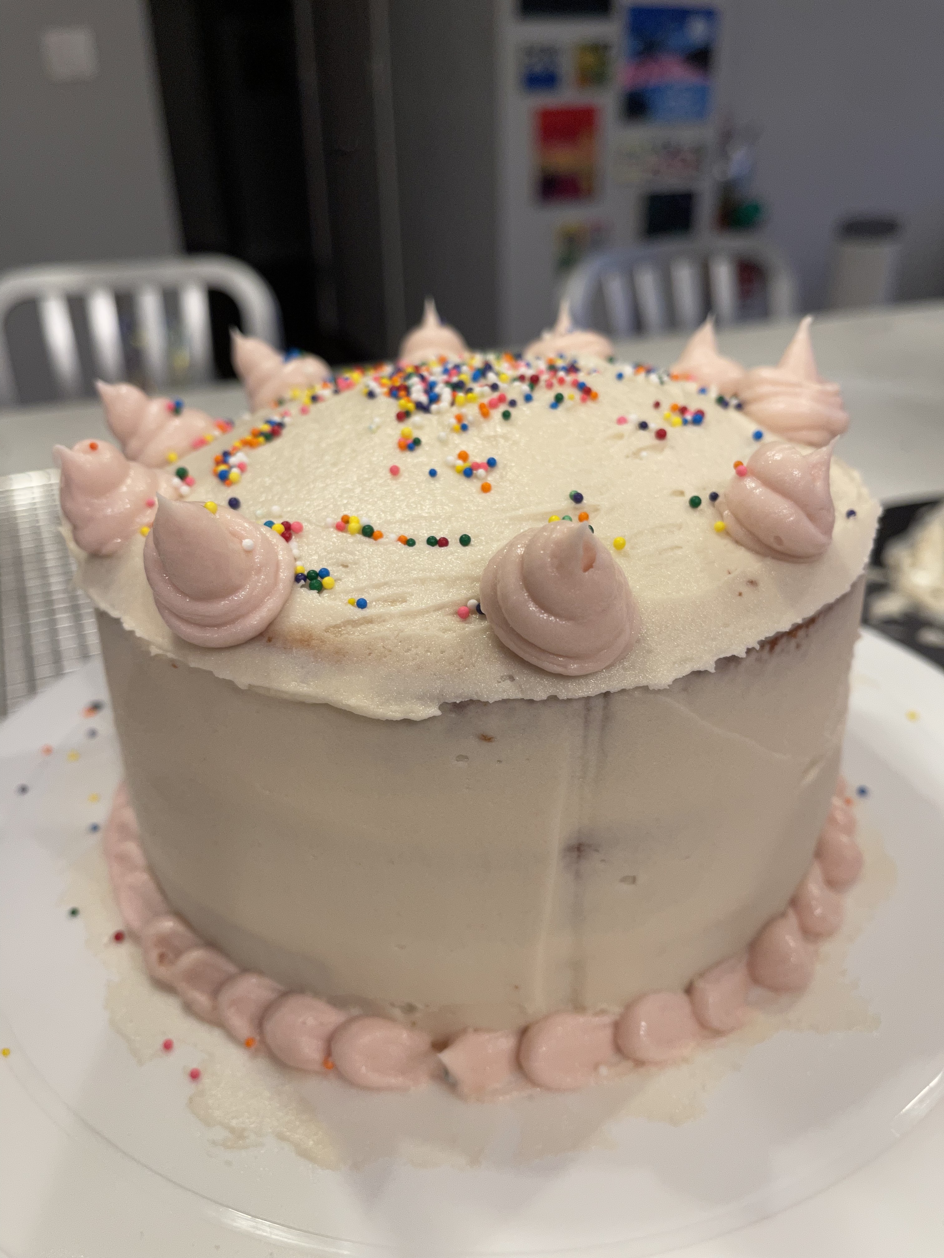 White frosted cake with pink frosting dollops