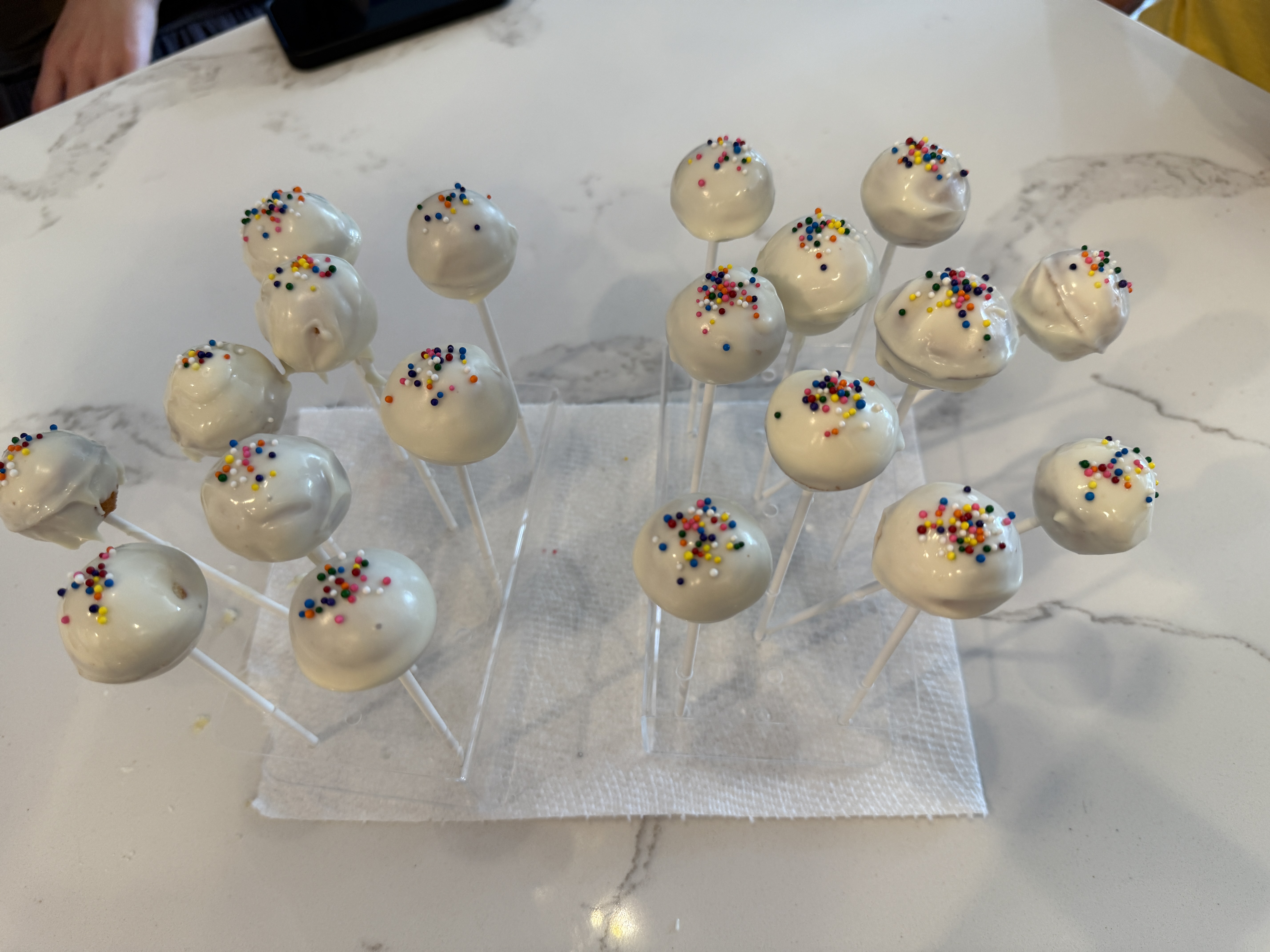 Cake pops with white frosting and rainbow sprinkles