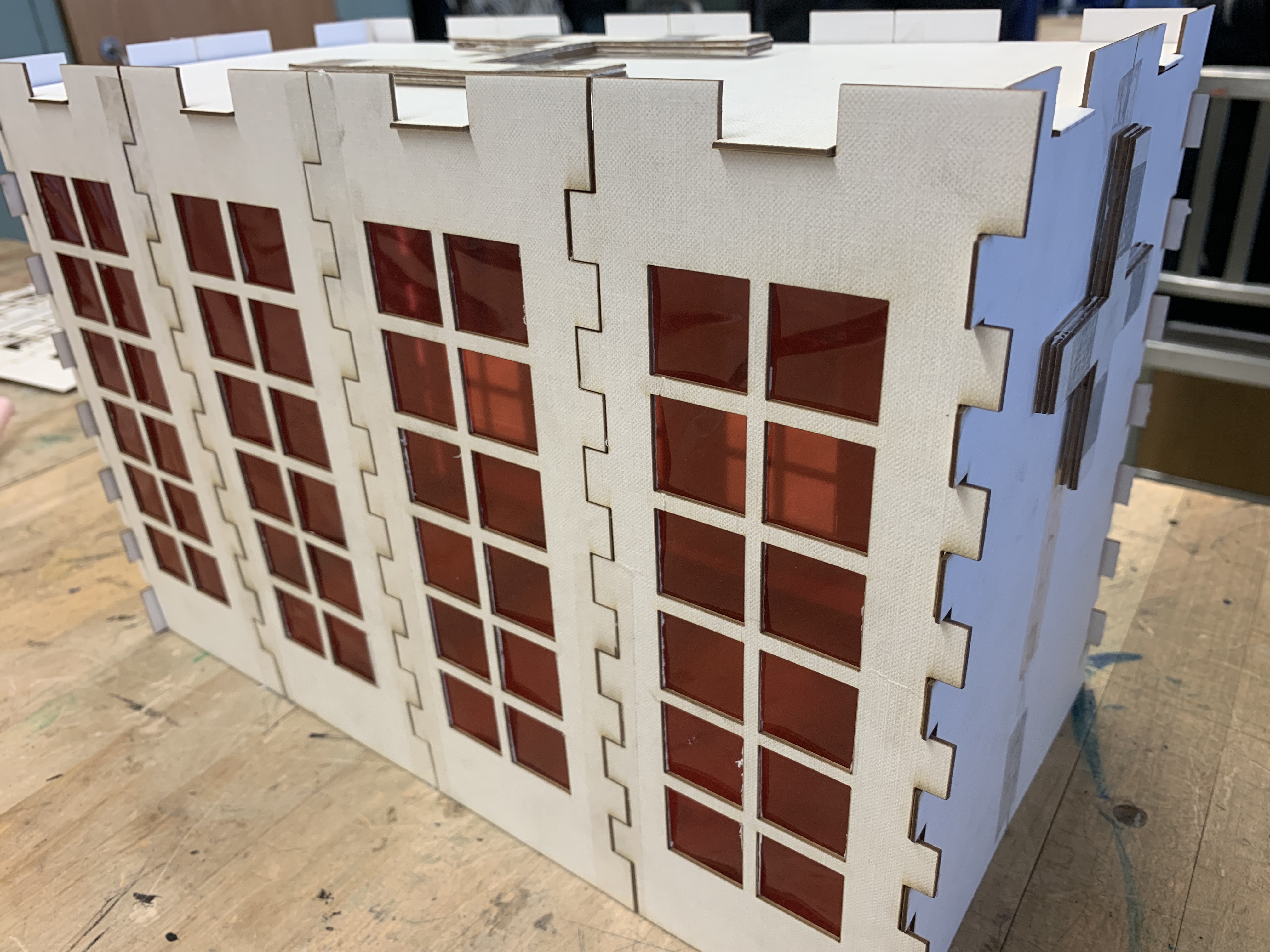 A thin building model with red windows.