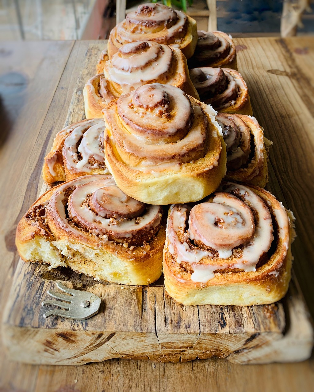 Cinnamon rolls lined up on a wooden cutting board.