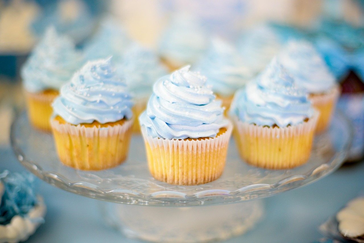 Vanilla cupcakes with light blue frosting sitting on a stand.