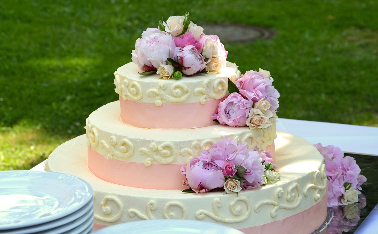 A 3-tiered pink and white cake covered in flowers.