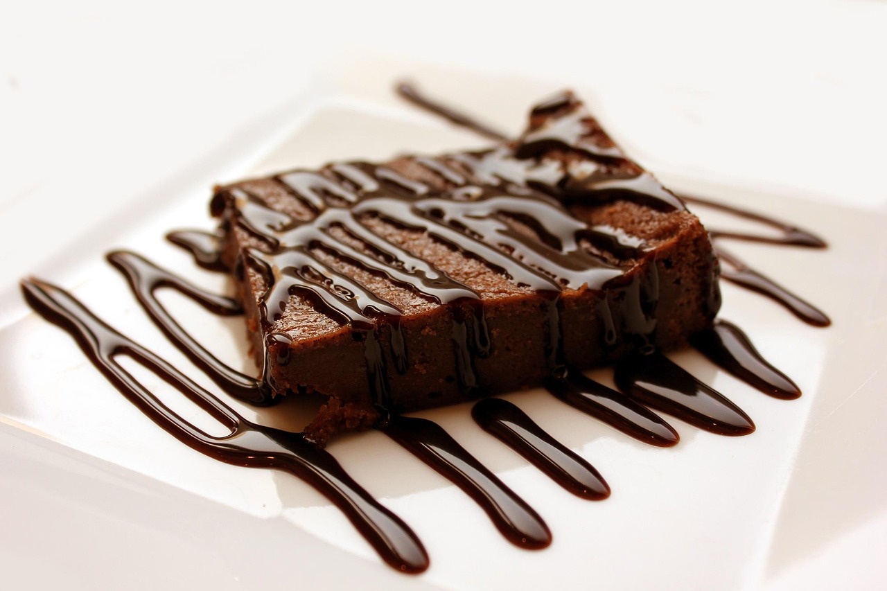 A brownie drizzled with chocolate on a plate.