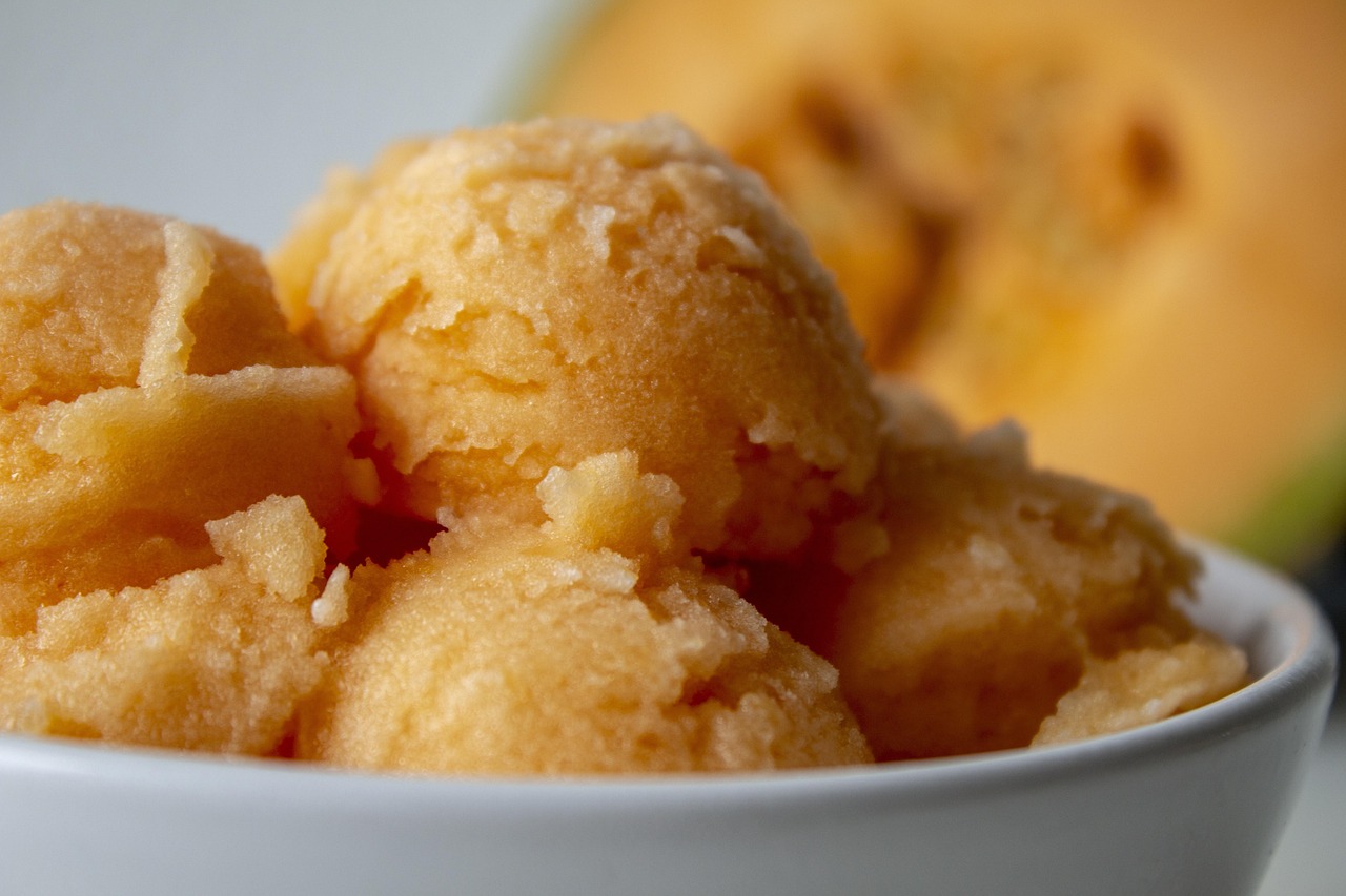 Many scoops of orange/yellow sorbet in a bowl.
