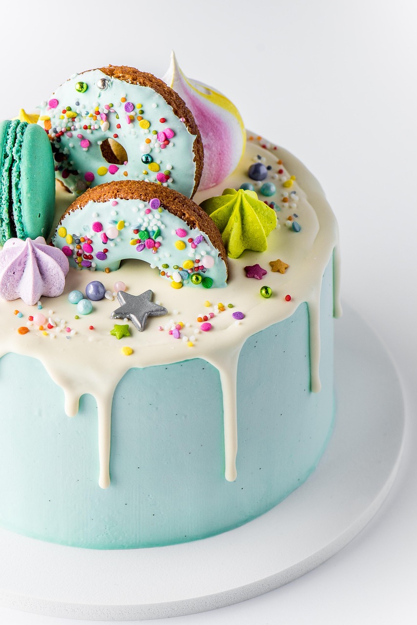 A cake covered in blue frosting with donuts and sprinkles on the top.